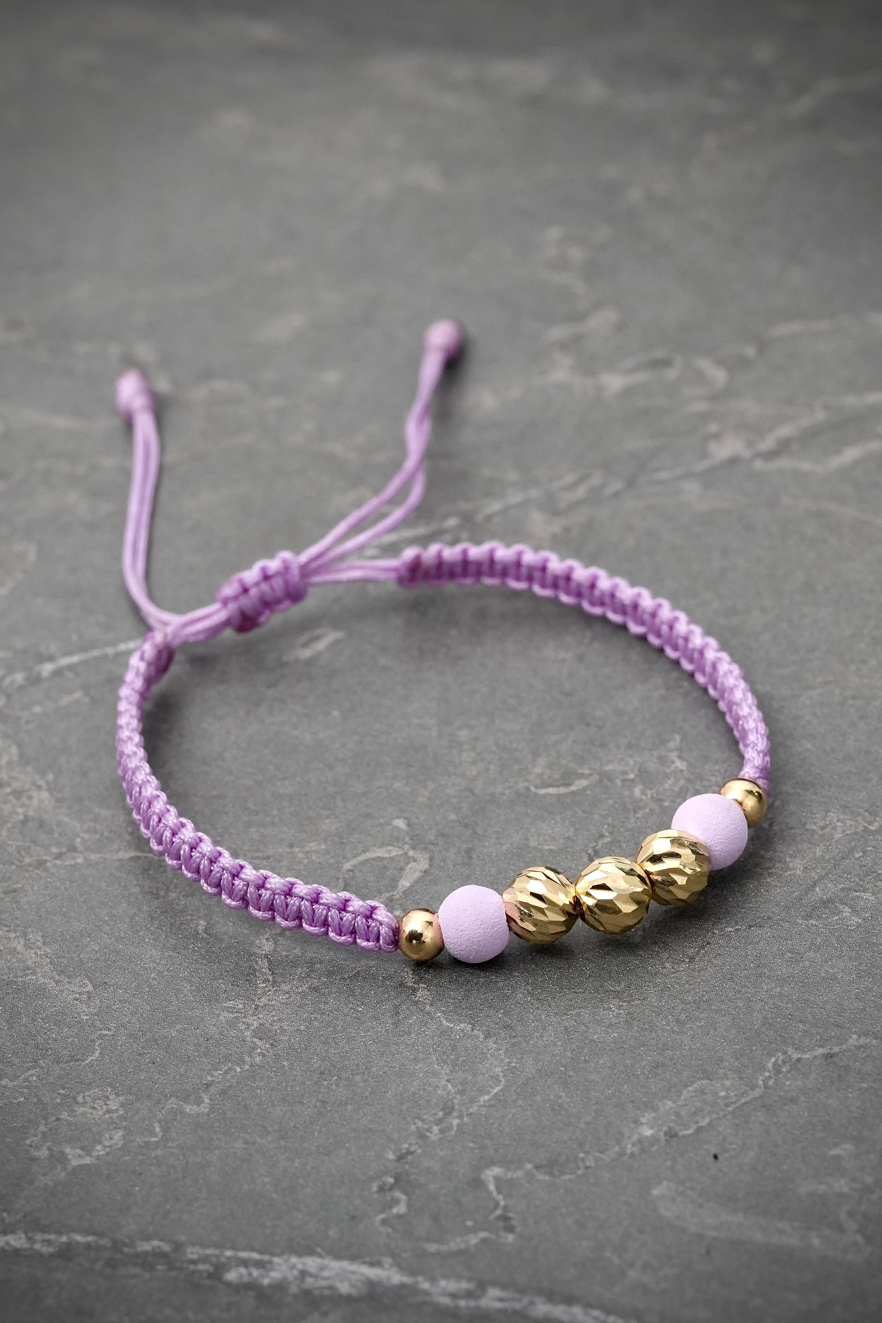 Pulsera en hilo morado con bolas diamantadas y lisas 0.75gr — Oro Amarillo