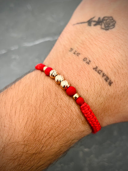 Pulsera en hilo rojo con bolas diamantadas y lisas 0.75gr — Oro Rosado