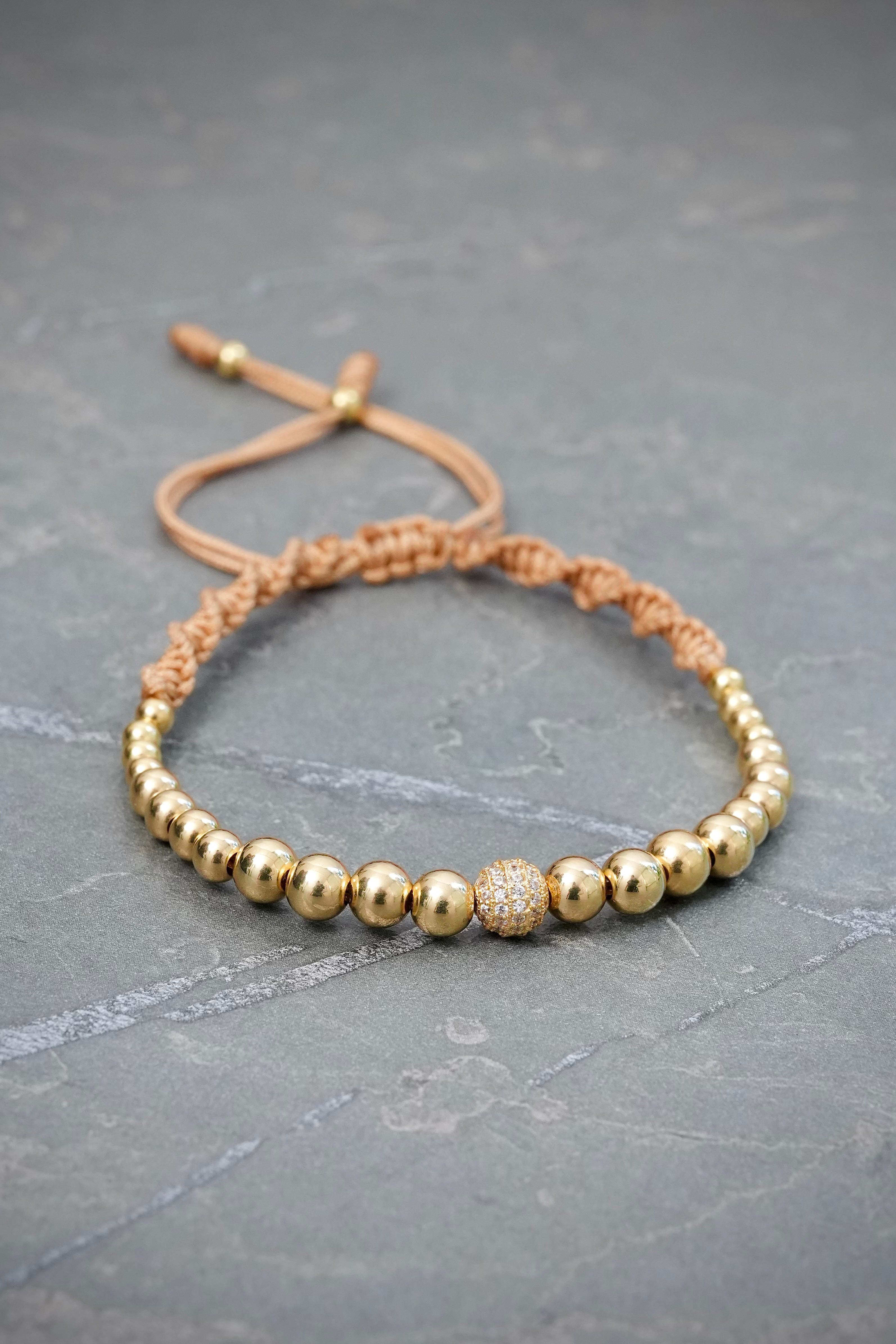 Pulsera en Hilo Beige con Bolas Lisas y Bola de Fuego 3gr — Oro Amarillo