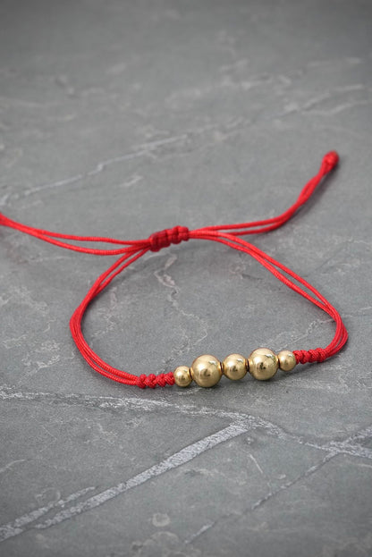 Pulsera en hilo rojo con bolas lisas 0.7gr — Oro Amarillo